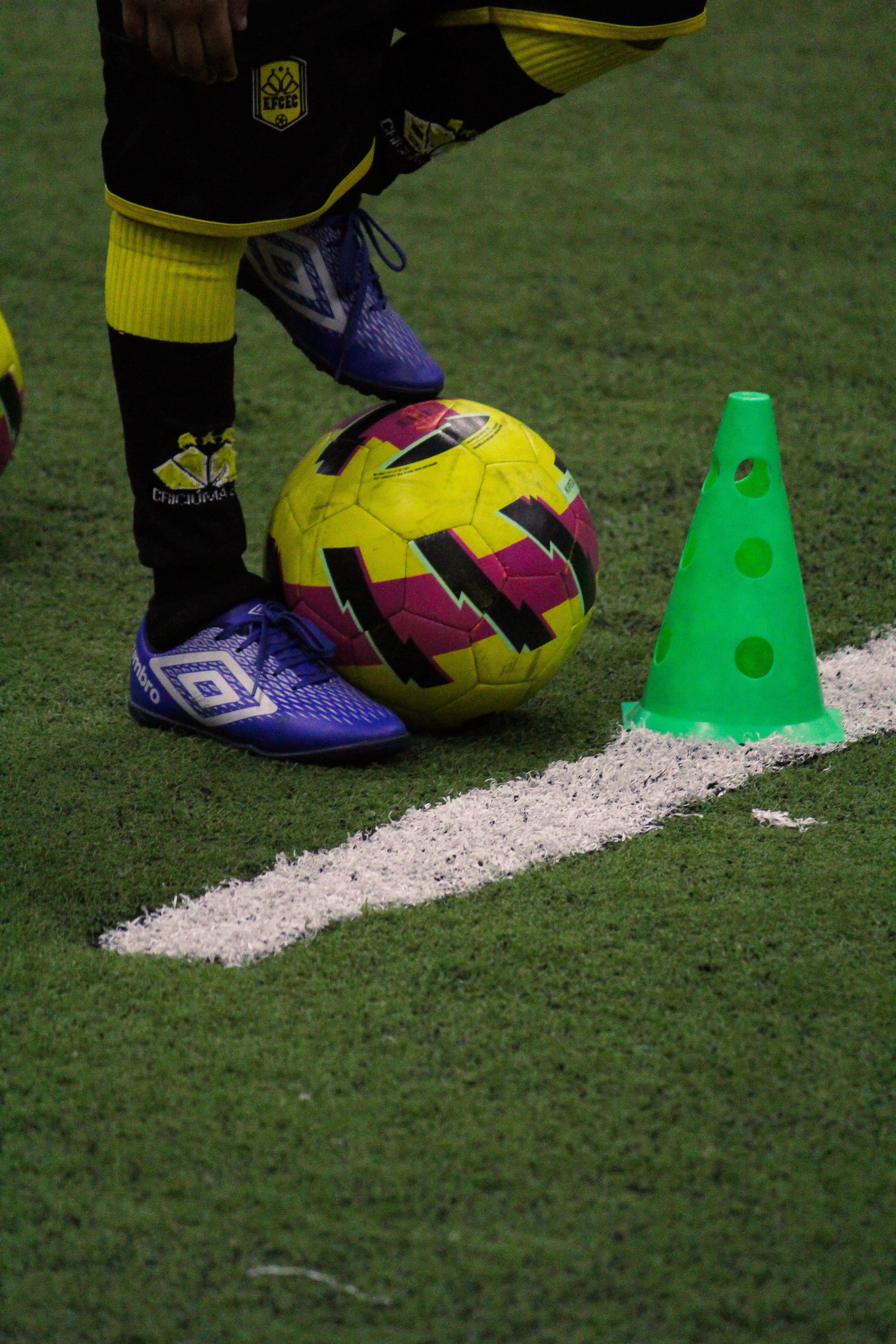 Imagem representando o pé de uma criança segurando uma bola de futebol, aluno da escolinha de futebol do Criciúma.